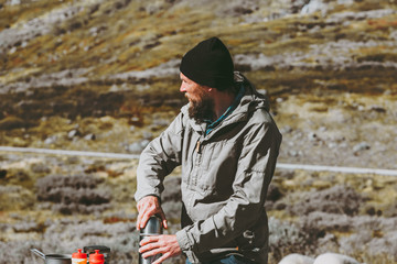 Man traveler holding thermos survival in mountains Travel lifestyle survival concept vacations into the wild