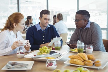 Businessman using digital table while sitting with colleagues in