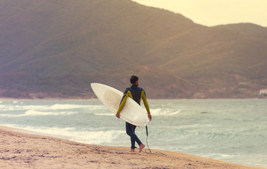 Surfer walking along the Beach in the evening for a surf, Surfer on the beach