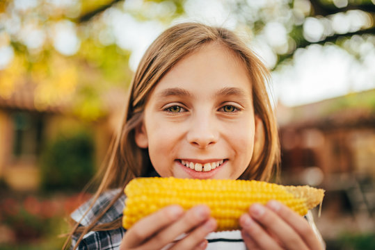 Girl eating sweet corn outdoor