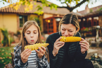 Girls eating sweet corn outdoor - obrazy, fototapety, plakaty