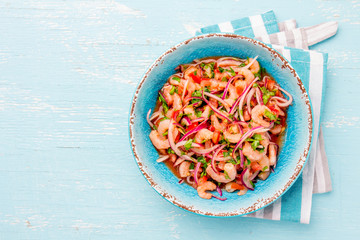 Ecuadorian shrimps ceviche sebiche with tomatoes in blue bowl, wooden blue background. Traditional...