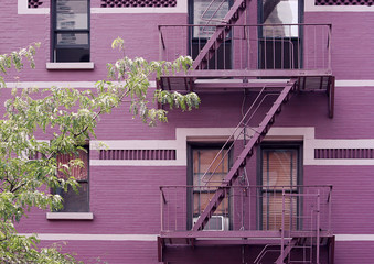 Fire escape stairs mounted to the outside of New York building with purple bricks