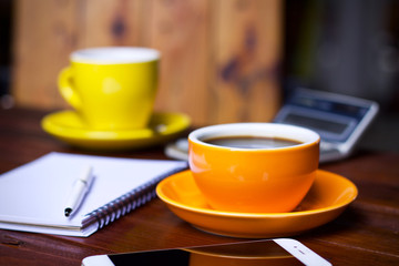 Coffee cup hot and notebook pen in desk