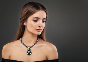 Beautiful Young Woman wearing Pearl Necklaces on Dark Background