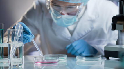 Scientist carefully carrying matured cell to another plate, conducting research - 182073761