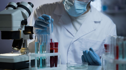 Worker of medical laboratory preparing glass for tests based on blood samples