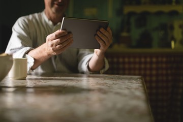 Senior man using digital tablet in kitchen