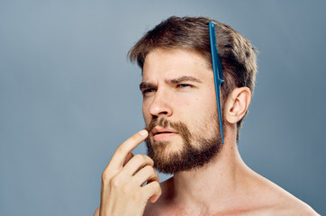 A man with a beard reflected on his hair a hairbrush on a gray background portrait