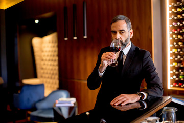 Handsome elegant businessman drinking red wine