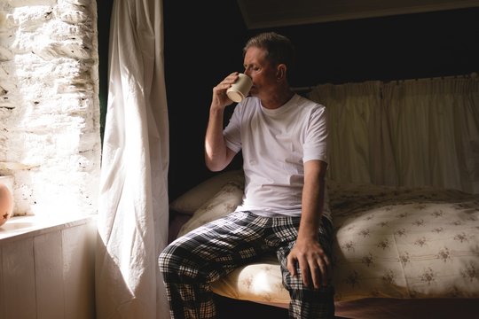 Senior man having coffee in bedroom