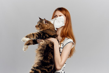A woman with a handkerchief holds a cat in her hands, an allergy