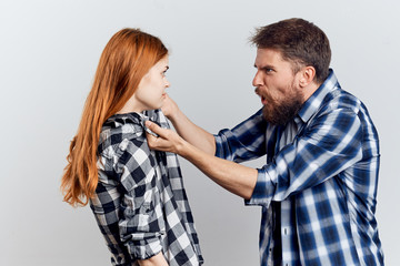 Young beautiful woman with a bearded man on a light background, attitude, quarrel, scandal