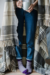 Feet in woollen socks. Woman is relaxing with a cup of hot drink and warming up her feet in woollen socks. - 182076541