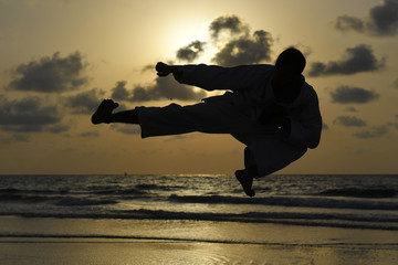 Silhouette of karate fighter at sunset on the beach © PROMA