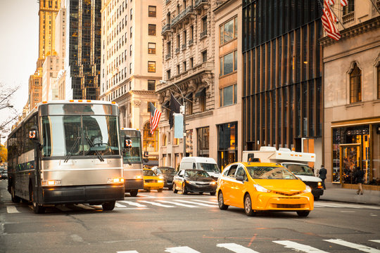 Generic New York City Street Scene With Taxi's Buses, Cars At Intersection And Unrecognizable People In Typical Upscale District