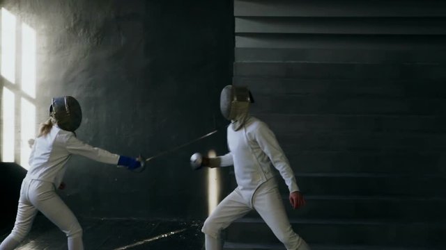 Slowmotion of Two fencers man and woman have fencing training indoors