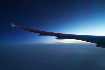 Fototapeta na wymiar Airplane wing and twilight sky before sunrise