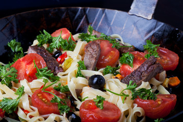 frische Pasta mit Tomaten und Oliven in einer Pfanne