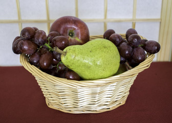 Grapes, an apple and a pear in wicker basket.