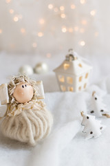 Christmas tree ornaments on a snow surface with christmas lights in the background. Christmas atmosphere. Close up on a christmas angel made handmande with felt ribbons and wool..