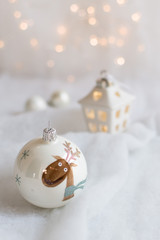 Christmas tree ornaments on a snow surface with christmas lights in the background. Christmas atmosphere. Close up on a christmas ball.