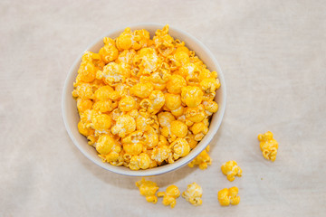 A bowl of freshly popped popcorn with cheese on a white background