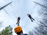 men at adventure climbing park walks by a rope simulator