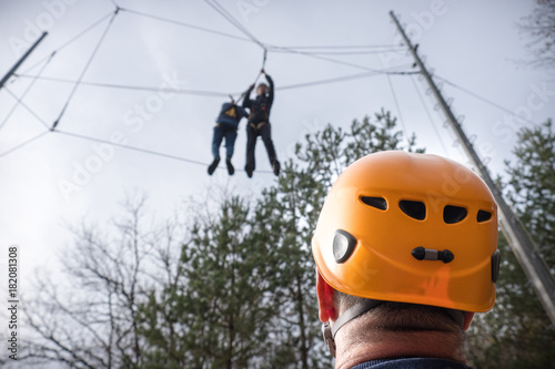 men at adventure climbing park walks by a rope simulator