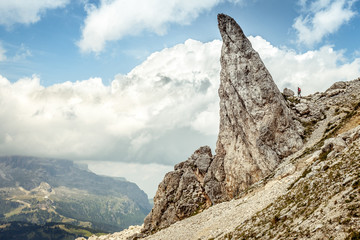 Trekker along path with awesome dolomitic pinnacle,  Settsass, Dolomites, Italy