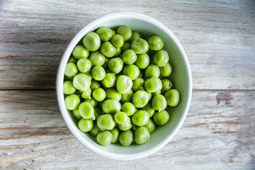 Peas in a bowl on wood.