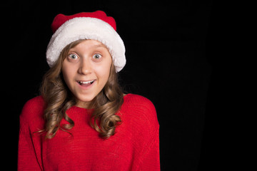 Excited young girl in red sweater and Santa's cap