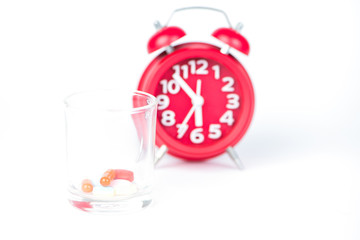 Dispensing glass and red clock show medicine time concept