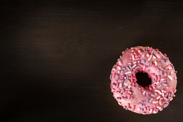 Donut on a wooden table. Unhealthy food. Dangers of obesity.