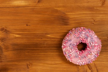 Fototapeta na wymiar Donut on a wooden table. Unhealthy food. Dangers of obesity.