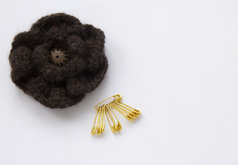 flower of thread for knitting, the button in the middle, on white background with gold pins
