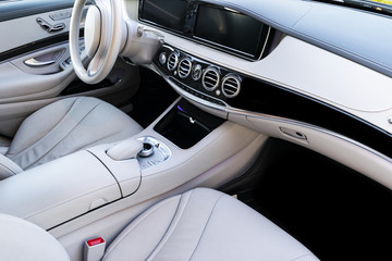 White leather interior of the luxury modern car. Leather comfortable white seats and multimedia. Steering wheel and dashboard. Automatic gear stick. Modern car interior details