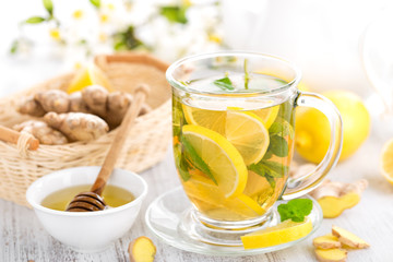 Flavored herbal tea with fresh lemon, ginger and mint leaves on white background, closeup