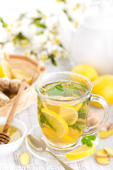 Flavored herbal tea with fresh lemon, ginger and mint leaves on white background, closeup