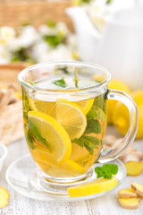 Flavored herbal tea with fresh lemon, ginger and mint leaves on white background, closeup
