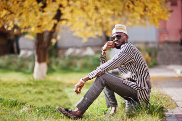 Portrait of stylish black african american man at hat and sunglasses against sunny autumn fall...