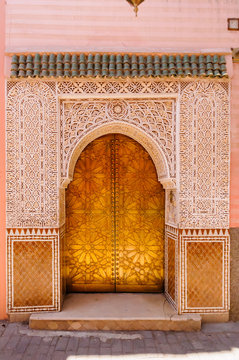 A gold metal door surrounded by intricate carved plaster in Marrakech, Morocco