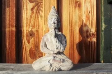 Buddha Figur vor einer Holzwand