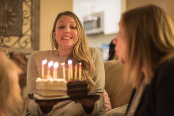 young woman holding birthday cake with glowng candles