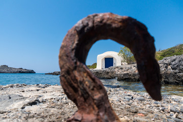 Fototapeta premium View of a small chapel by the sea in Kythera island in Greece through a rusty hook 