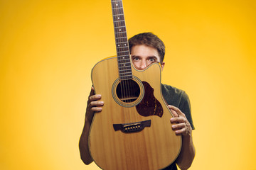 Man with a beard holding a guitar on a yellow background musical instrument