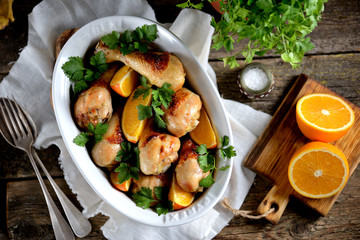 Baked chicken drumstick with orange  on an old wooden background. Rustic style.