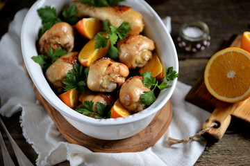 Baked chicken drumstick with orange  on an old wooden background. Rustic style.