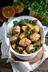 Baked chicken drumstick with orange  on an old wooden background. Rustic style.