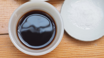 Soy sauce and salt in ceramic cup and plate top view